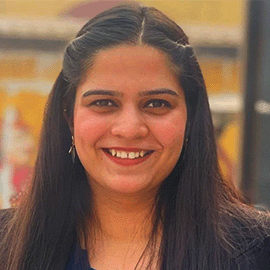 A woman with a centre part smiles and looks at the camera.
